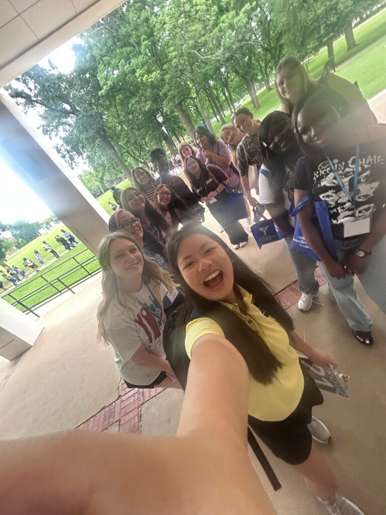 Students attending orientation posing for a photo near the blue horseshoe at MTSU with their Student Orientation Assistant.