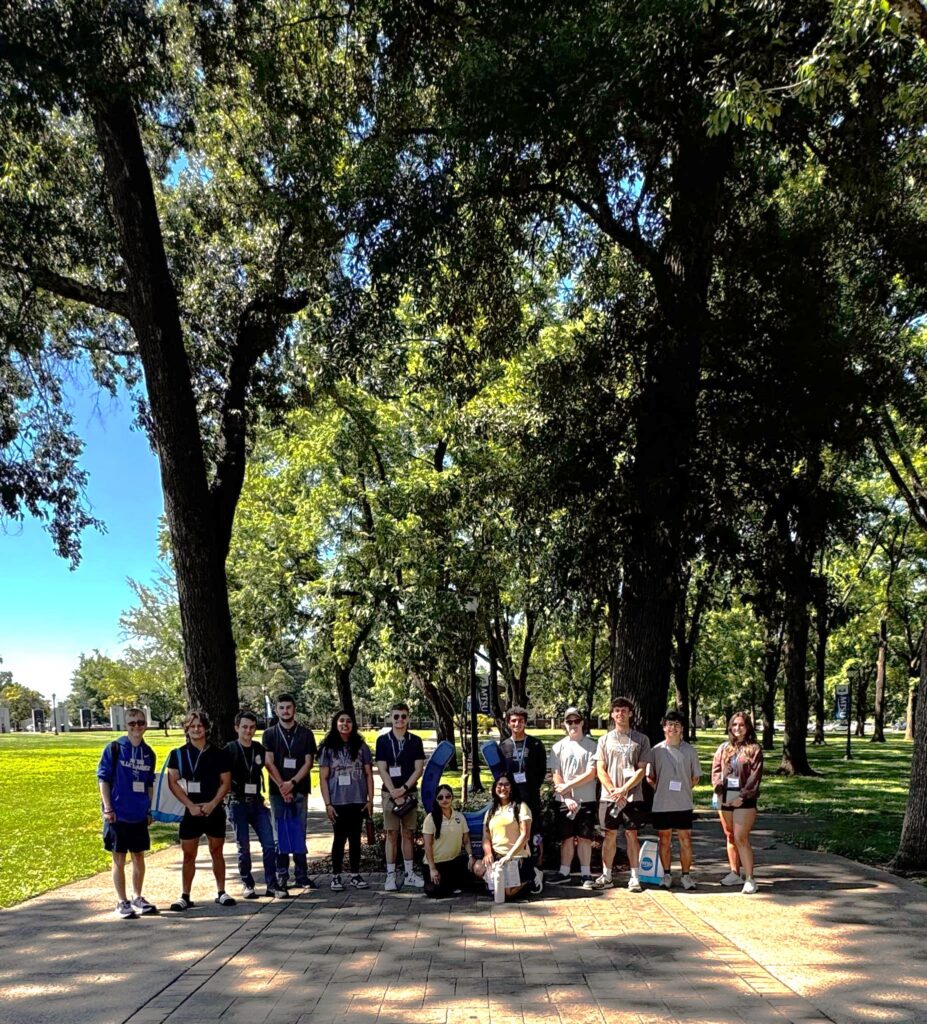 Students attending orientation posing for a photo at the blue horseshoe at MTSU with their Student Orientation Assistants.