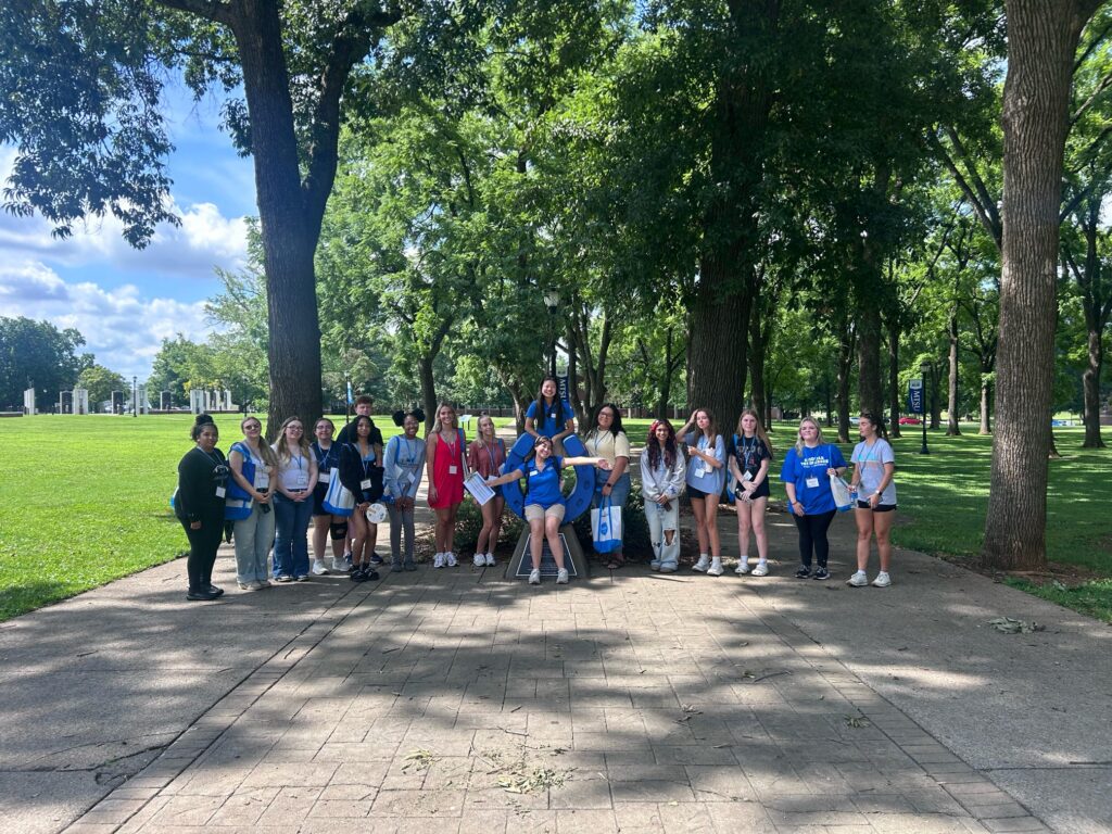 Students attending orientation posing for a photo at the blue horseshoe at MTSU with their Student Orientation Assistant.