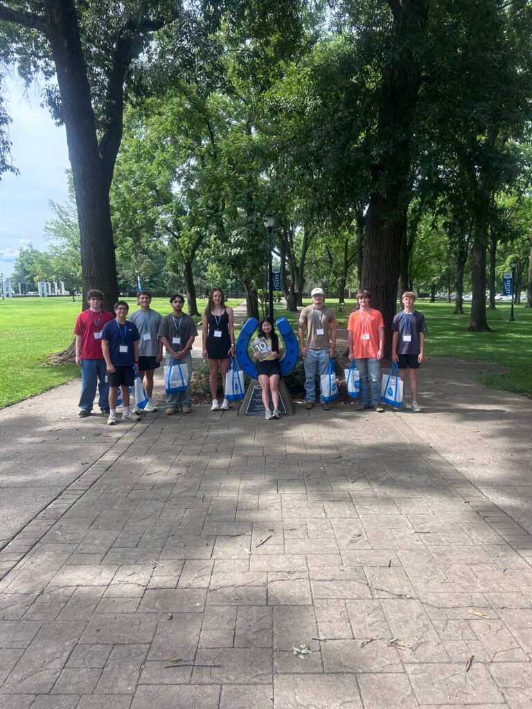 Students in Group 10 of orientation posing for a photo at the blue horseshoe at MTSU with their Student Orientation Assistant.