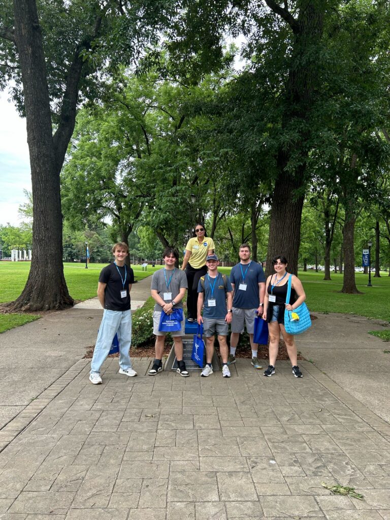 Students attending orientation posing for a photo at the blue horseshoe at MTSU with their Student Orientation Assistant.