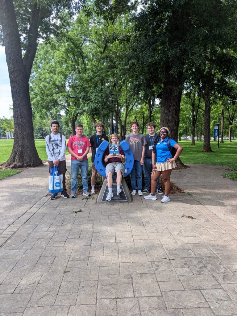 Students in Group 23 of orientation posing for a photo at the blue horseshoe at MTSU with their Student Orientation Assistant.