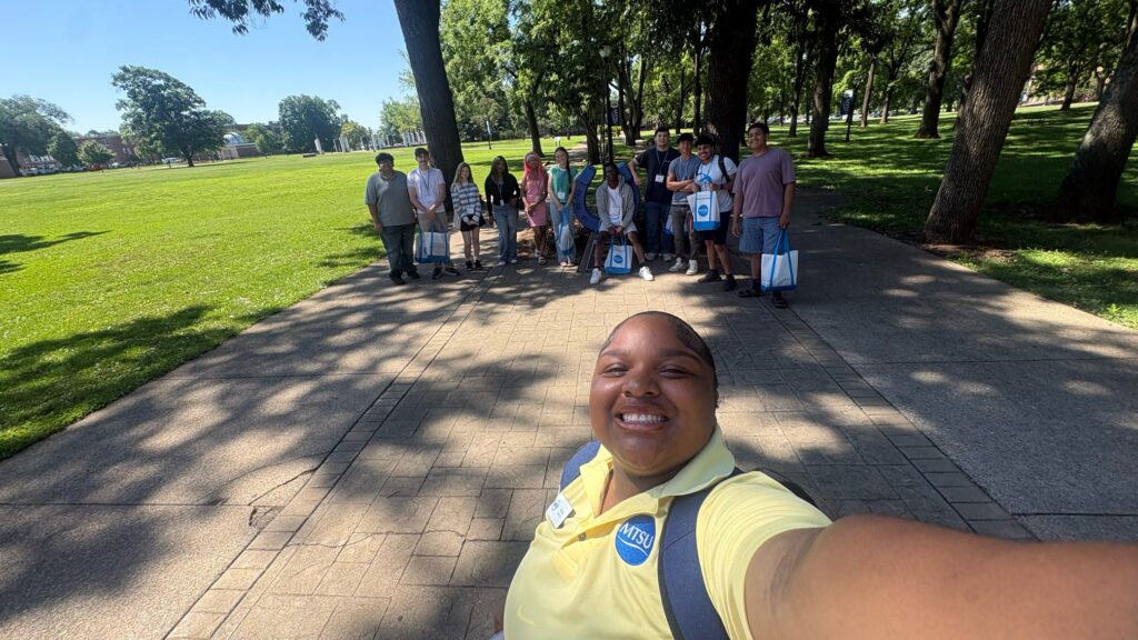 Students attending orientation posing for a photo at the blue horseshoe at MTSU with their Student Orientation Assistant.