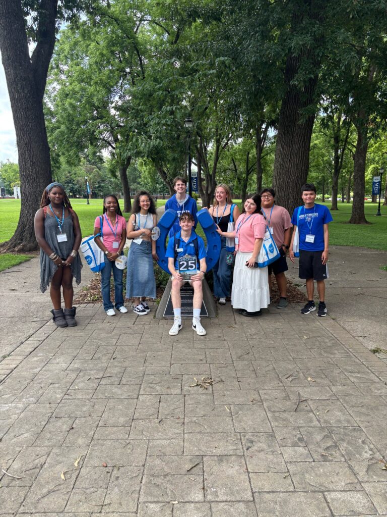 Students in Group 25 of orientation posing for a photo at the blue horseshoe at MTSU with their Student Orientation Assistant.