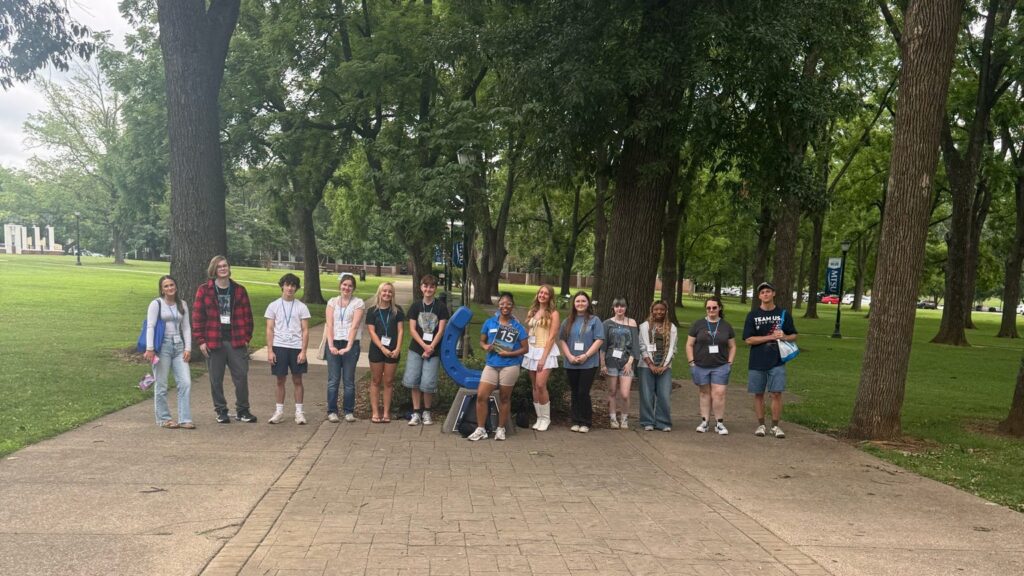Students in Group 15 of orientation posing for a photo at the blue horseshoe at MTSU with their Student Orientation Assistant.