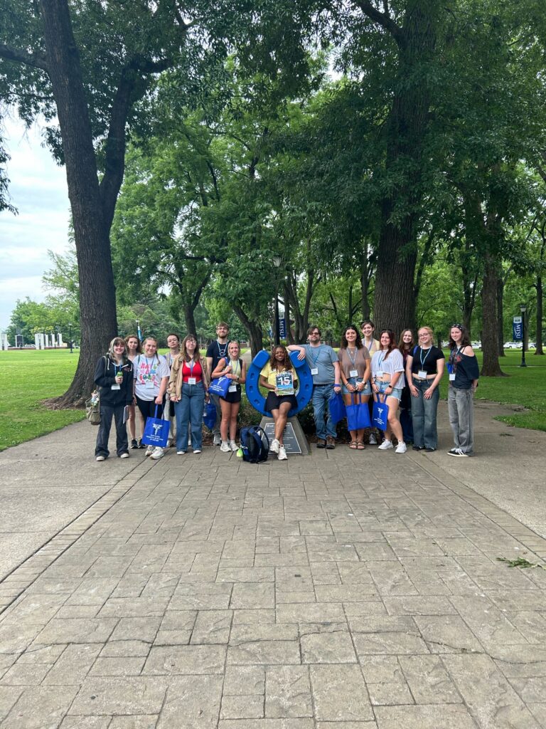 Students in Group 15 of orientation posing for a photo at the blue horseshoe at MTSU with their Student Orientation Assistant.