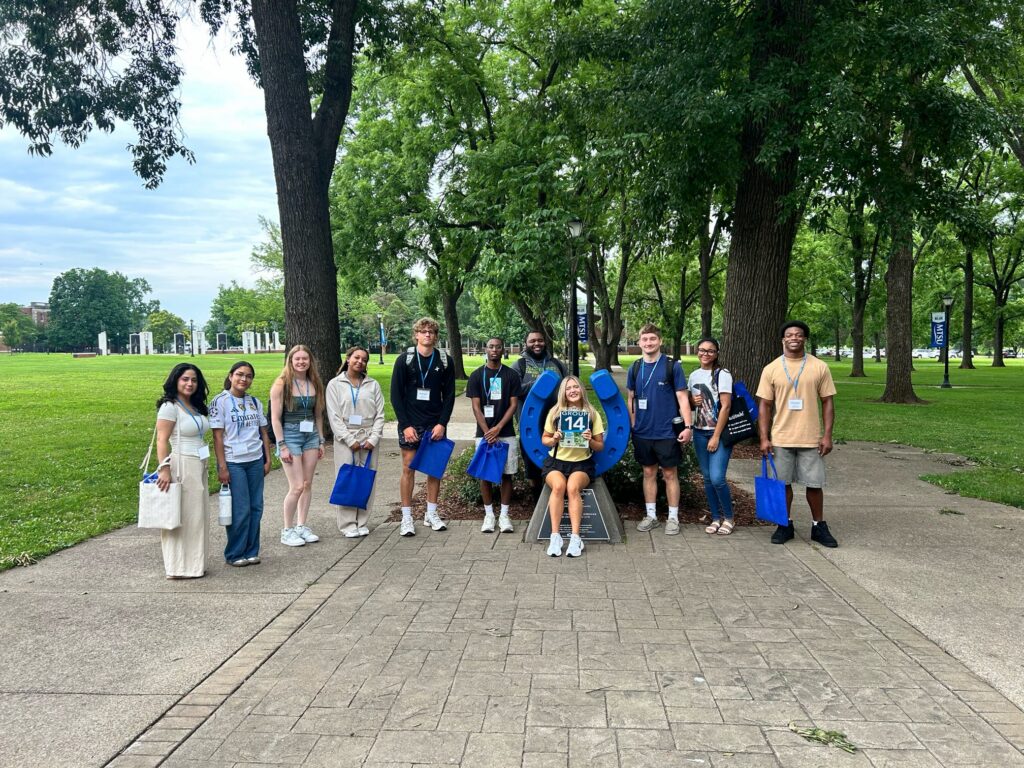 Students in Group 14 of orientation posing for a photo at the blue horseshoe at MTSU with their Student Orientation Assistant.