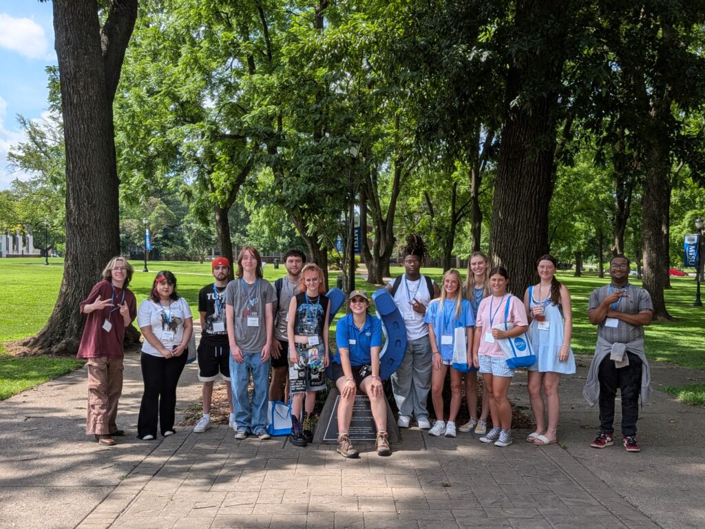 Students attending orientation posing for a photo at the blue horseshoe at MTSU with their Student Orientation Assistant.