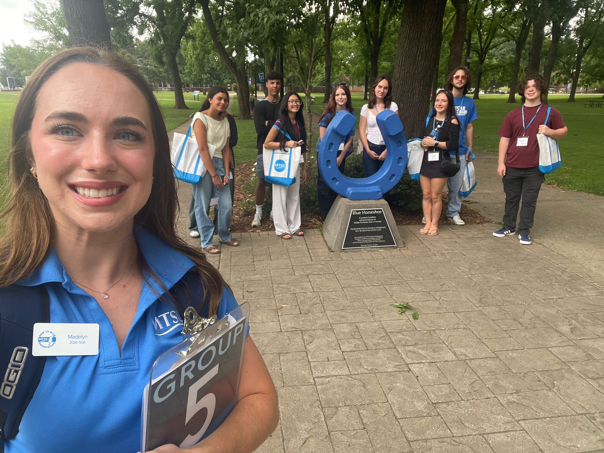 Students in Group 5 of orientation posing for a photo at the blue horseshoe at MTSU with their Student Orientation Assistant.