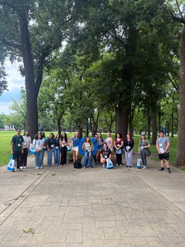 Students in Group 5 of orientation posing for a photo at the blue horseshoe at MTSU with their Student Orientation Assistant.