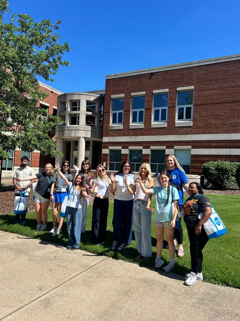 Students attending Orientation posing together outside the Cason Kennedy Nursing Building.