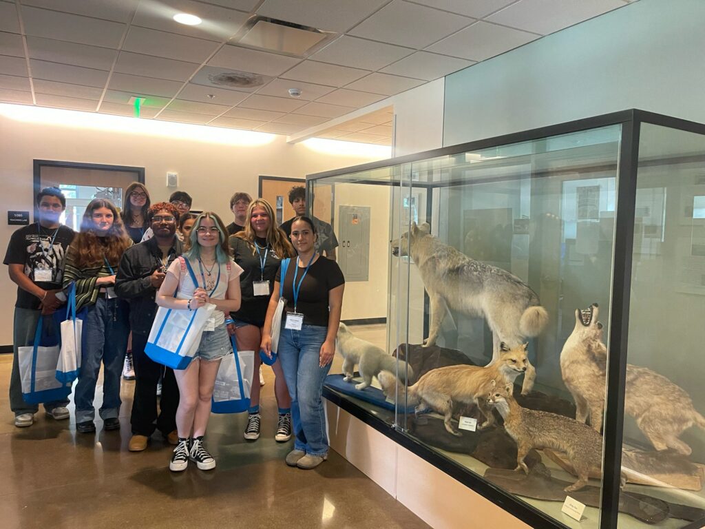 Students attending orientation posing for a picture beside an animal exhibit