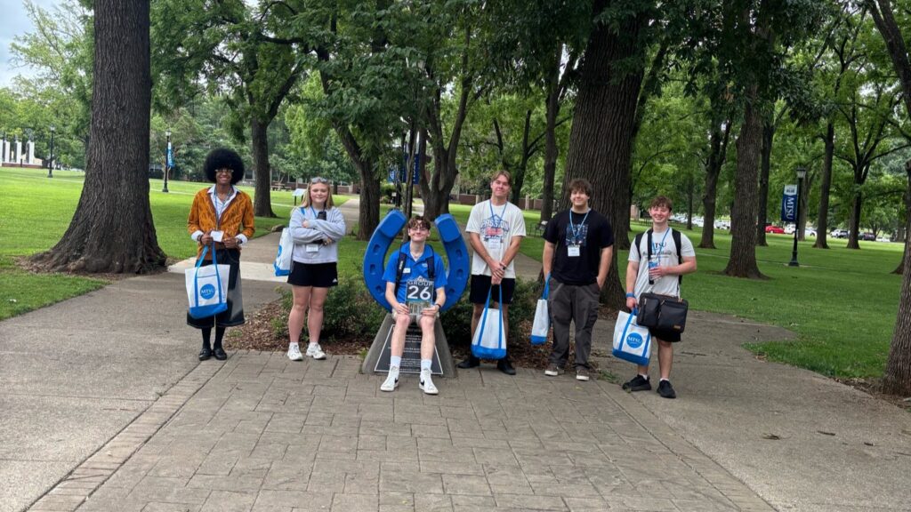 Students in Group 26 of orientation posing for a photo at the blue horseshoe at MTSU with their Student Orientation Assistant.