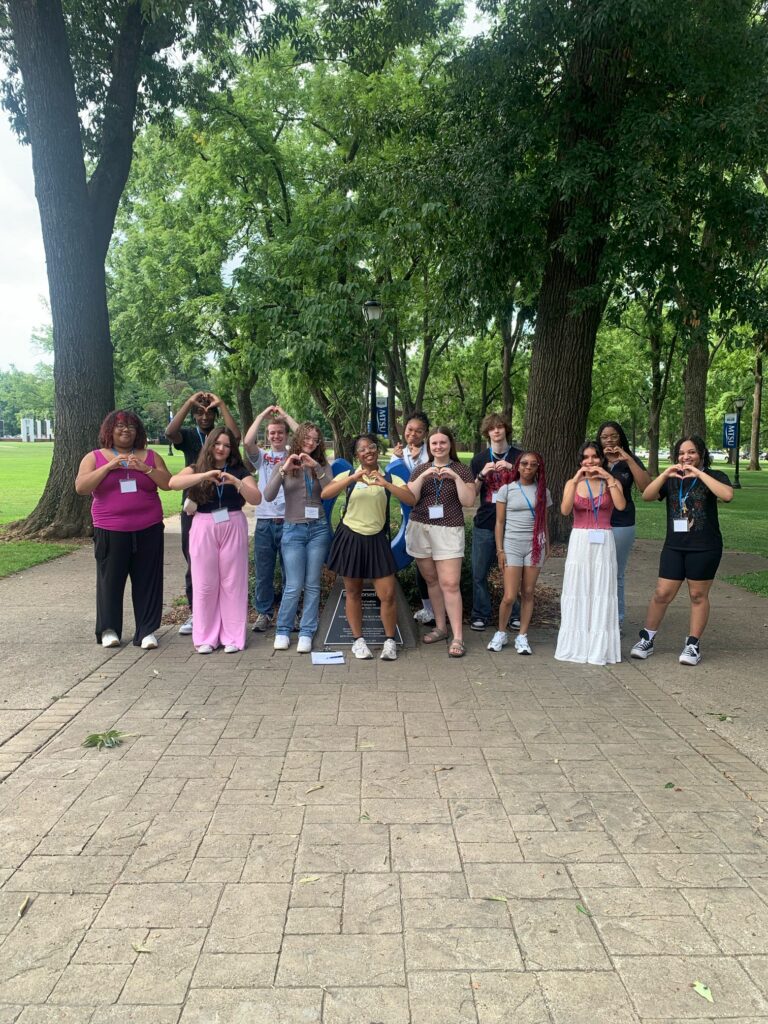 Students attending New to Blue Orientation posing for a photo with their Student Orientation Assistants, making hearts with their hands.