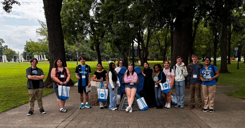 Students in Group 25 of orientation posing for a photo at the blue horseshoe at MTSU with their Student Orientation Assistant.