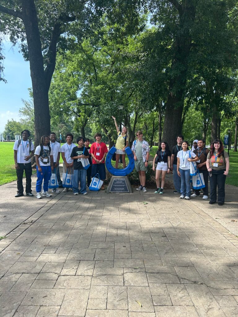 Students attending orientation posing for a photo at the blue horseshoe at MTSU with their Student Orientation Assistant.