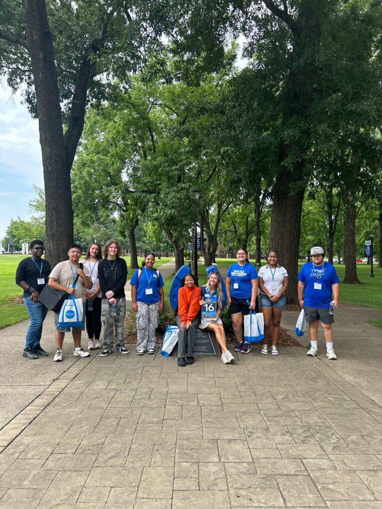 Students in Group 16 of orientation posing for a photo at the blue horseshoe at MTSU with their Student Orientation Assistant.