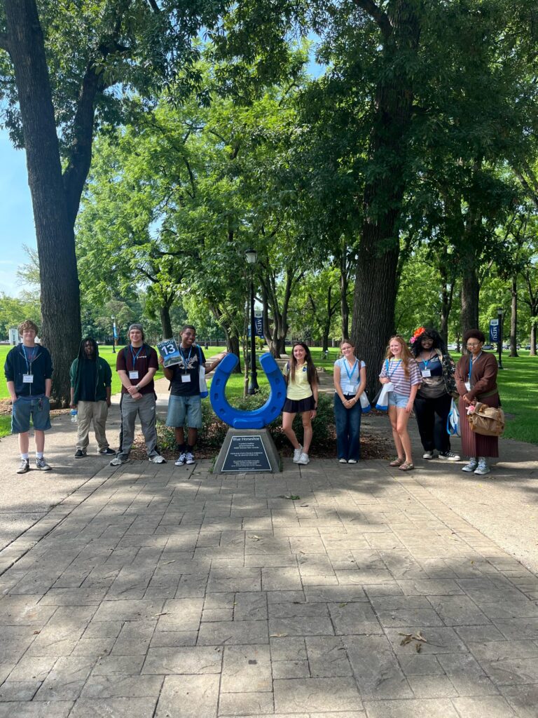 Students in Group 13 of orientation posing for a photo at the blue horseshoe at MTSU with their Student Orientation Assistant.