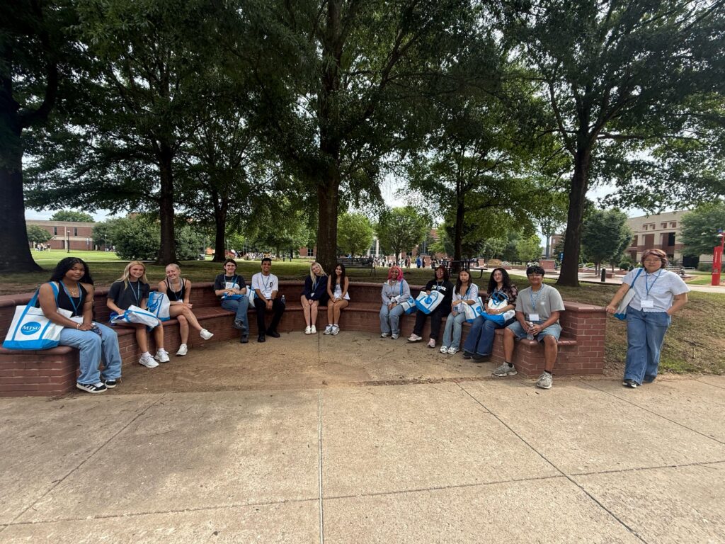 Students attending orientation sitting outside in a semi-circle.