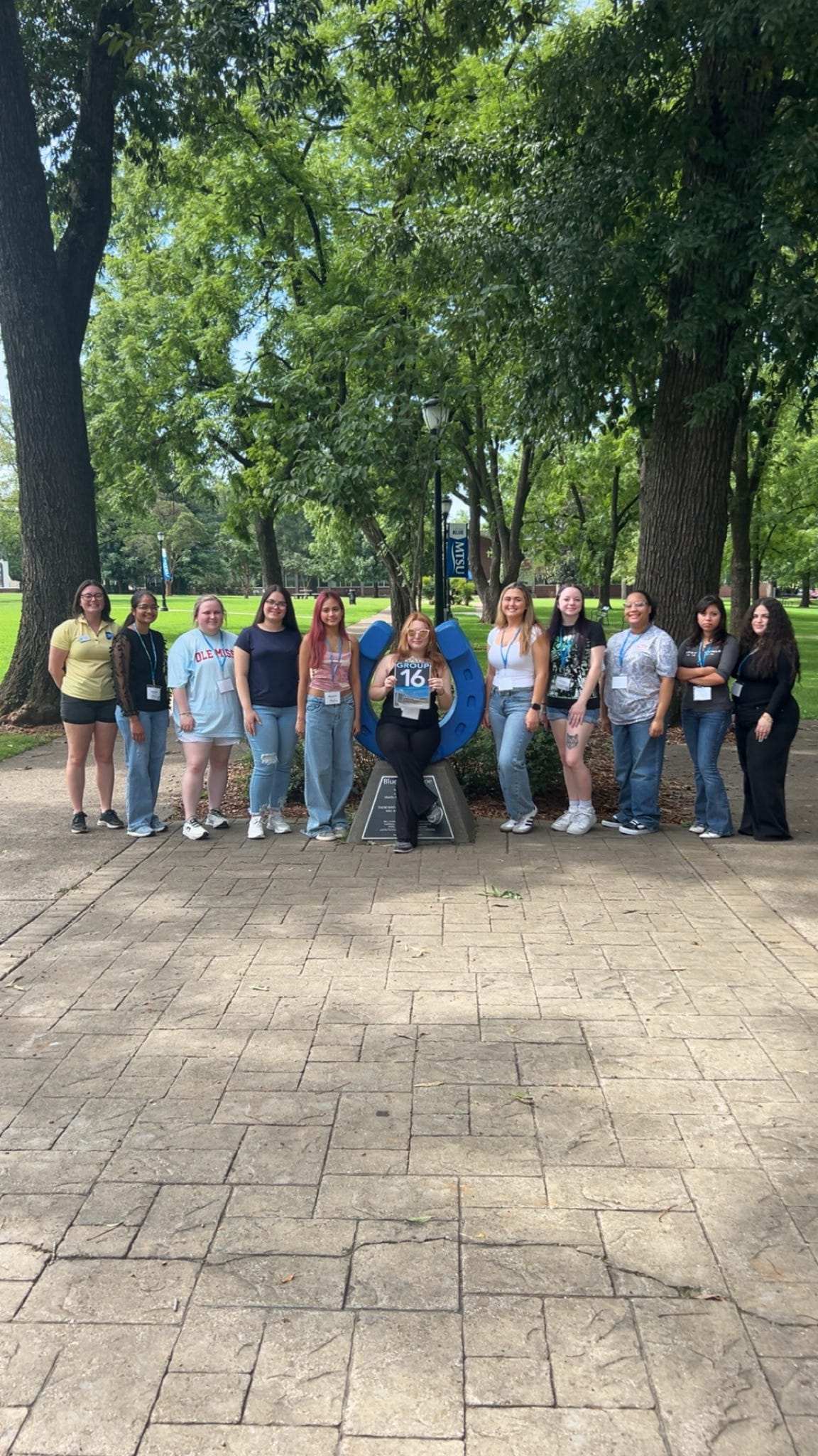Students in Group 16 of orientation posing for a photo at the blue horseshoe at MTSU with their Student Orientation Assistant.