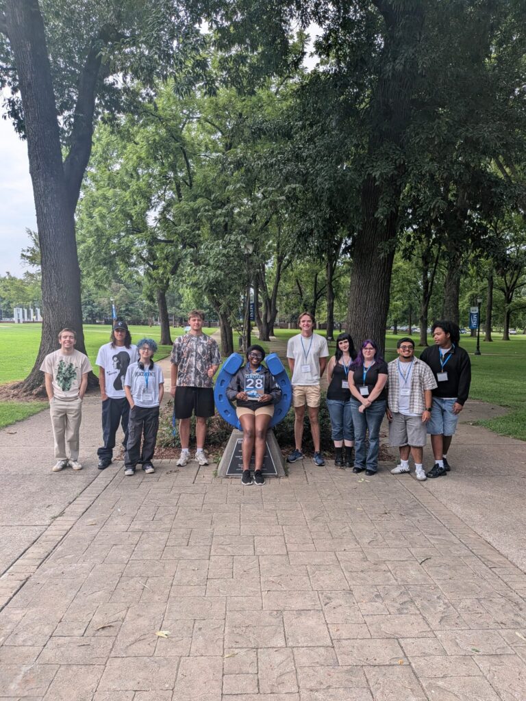 Students in Group 28 of orientation posing for a photo at the blue horseshoe at MTSU with their Student Orientation Assistant.