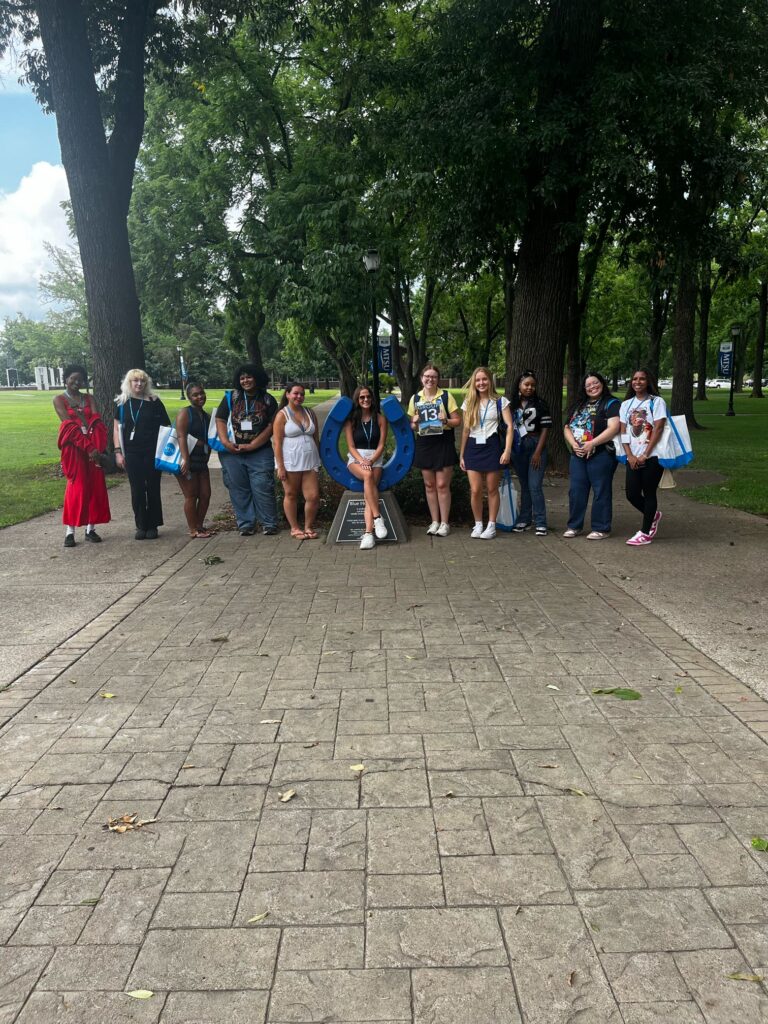 Students in Group 13 of orientation posing for a photo at the blue horseshoe at MTSU with their Student Orientation Assistant.