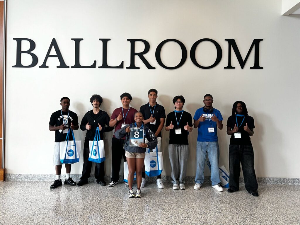 Students in Group 8 of orientation posing for a photo outside the Ballroom in the Student Union with their Student Orientation Assistant.