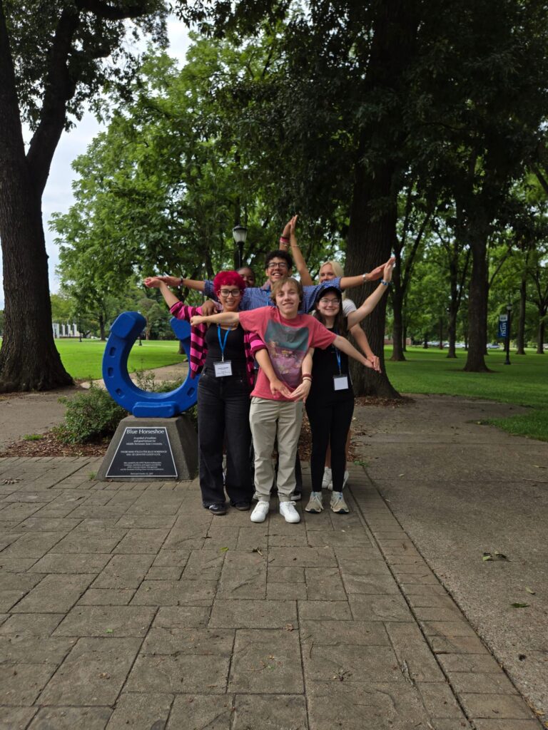 Students standing in front of the Blue Horseshoe in Walnut Grove, posing their arms in the shape of a star.