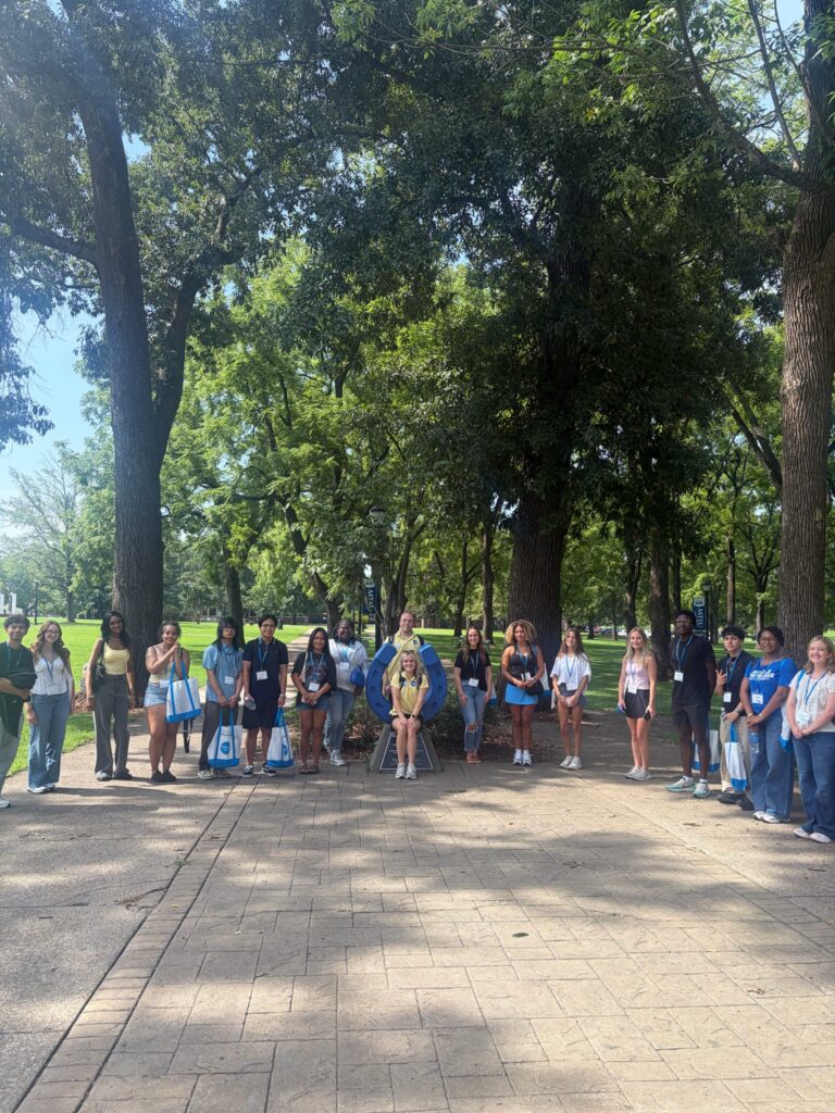 Students attending orientation posing for a photo at the blue horseshoe at MTSU with their Student Orientation Assistants.