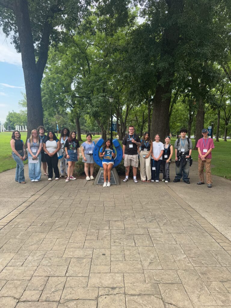 Students in Group 5 of orientation posing for a photo at the blue horseshoe at MTSU with their Student Orientation Assistant.