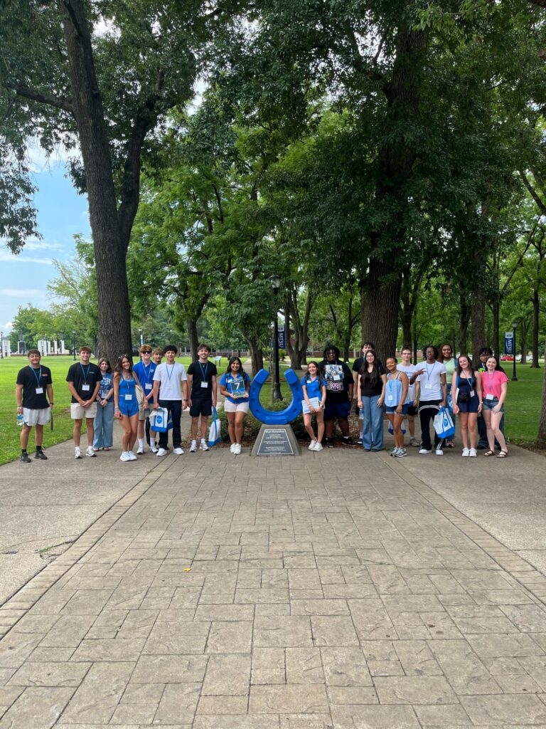 Students in Group 7 of orientation posing for a photo at the blue horseshoe at MTSU with their Student Orientation Assistant.