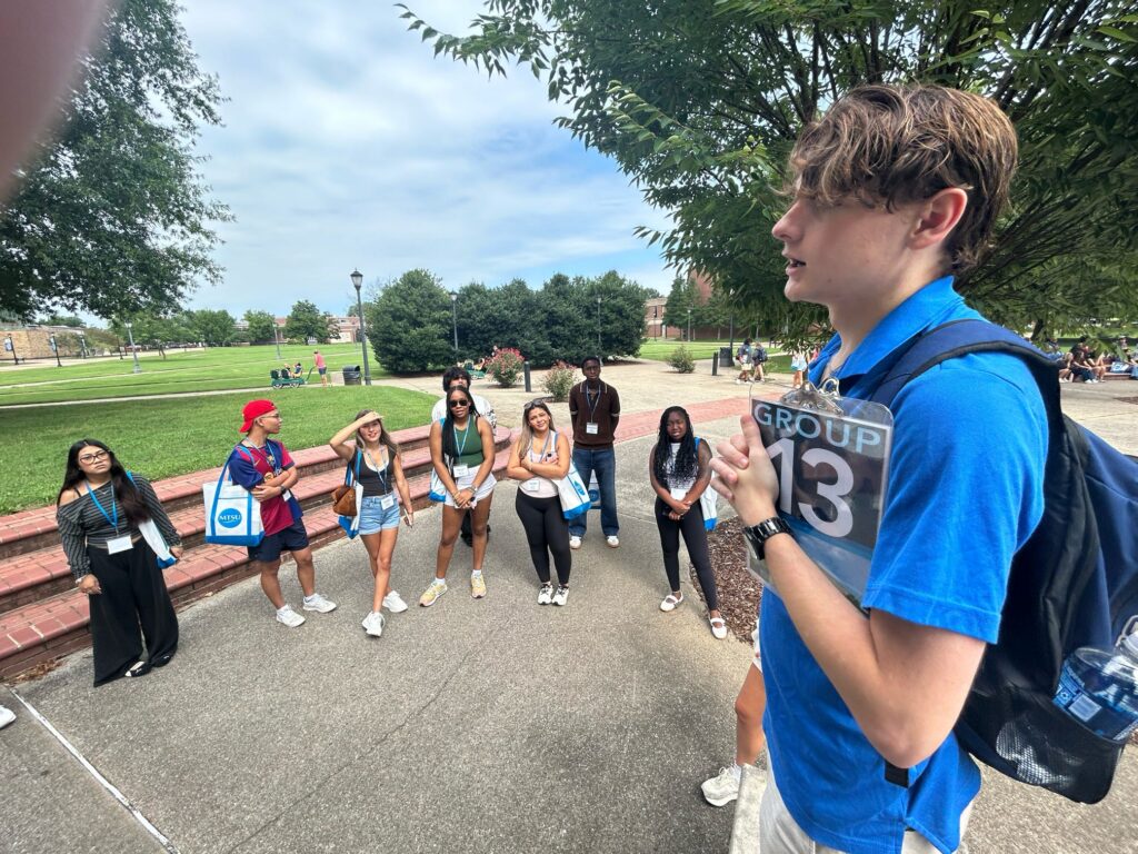 Students in Group 13 of orientation standing outside with their Student Orientation Assistant.