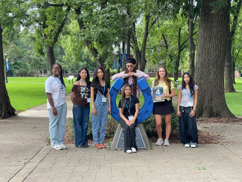 Students in Group 4 of orientation posing for a photo at the blue horseshoe at MTSU with their Student Orientation Assistant.