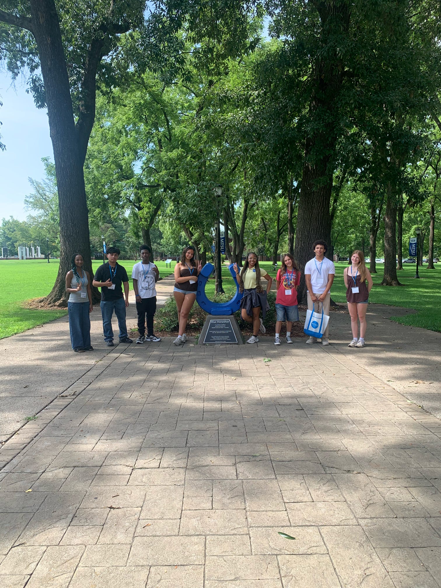 Students attending orientation posing for a photo at the blue horseshoe at MTSU with their Student Orientation Assistant.
