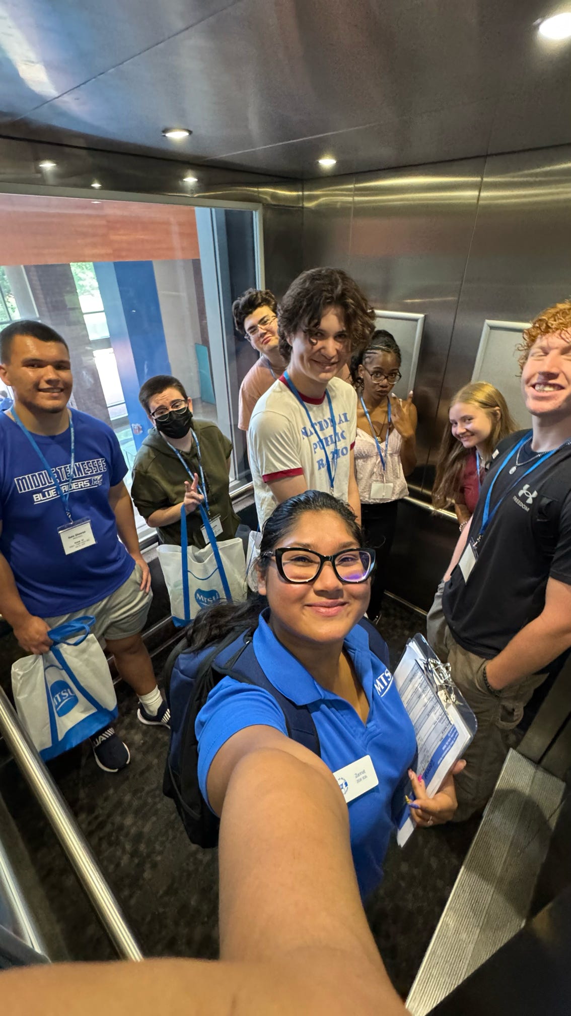 Students attending orientation standing inside the Student Union's elevator with their Student Orientation Assistant.