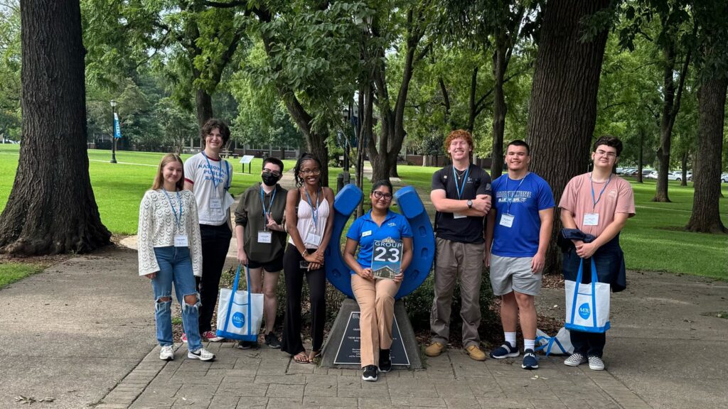 Students in Group 23 of orientation posing for a photo at the blue horseshoe at MTSU with their Student Orientation Assistant.