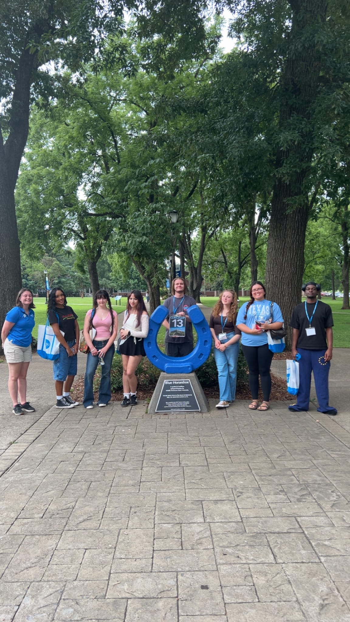 Students in Group 13 of orientation posing for a photo at the blue horseshoe at MTSU with their Student Orientation Assistant.