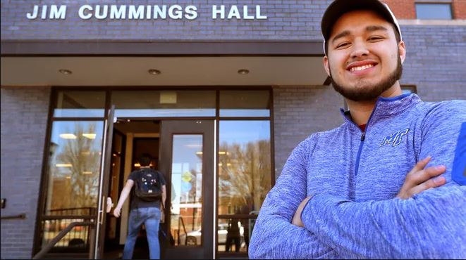 student in front of campus building