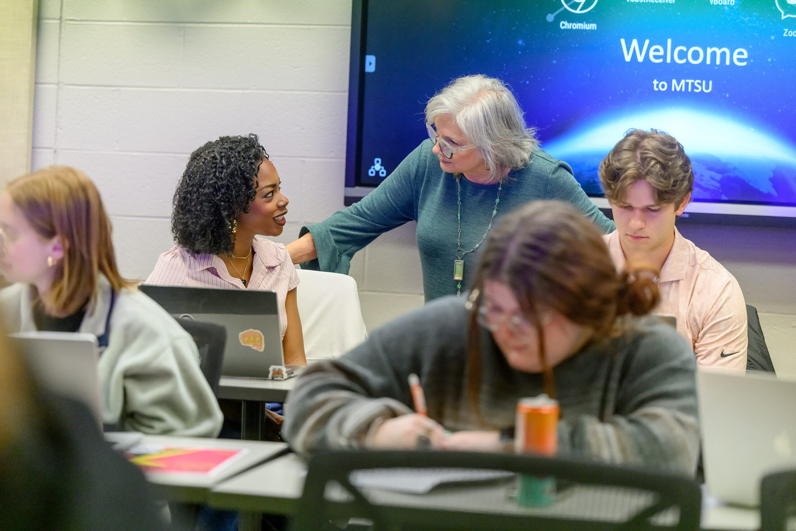 Entertainment Law professor standing behind 2 rows of students, speaking to one of them.